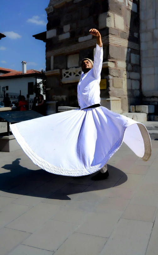 a woman in white with a dress and long sleeves dancing outside