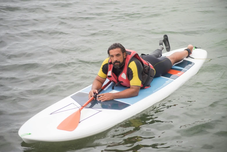 a man laying down on top of a surfboard in the water