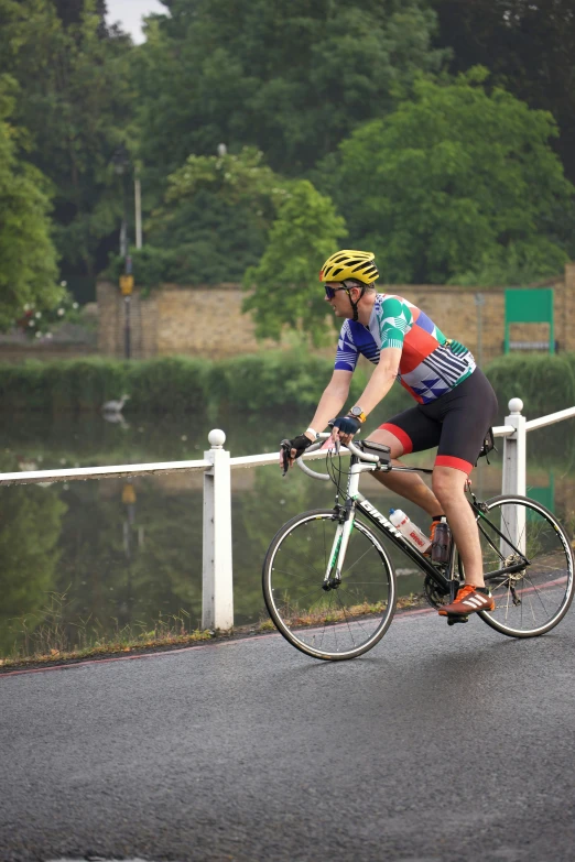 man riding bike down the road near a river