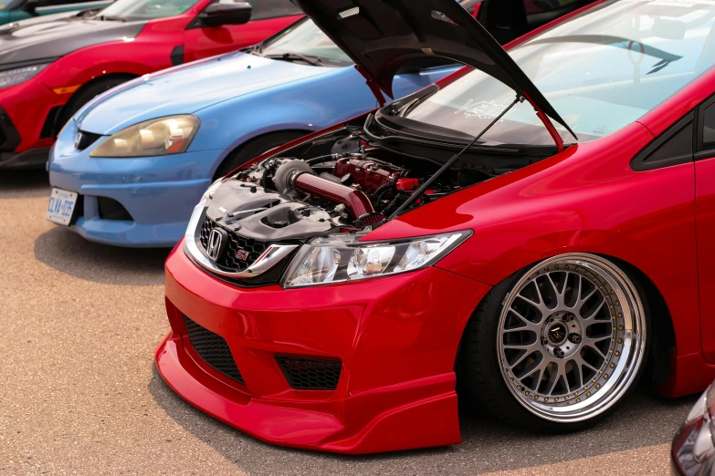 red cars with their hood open in a parking lot