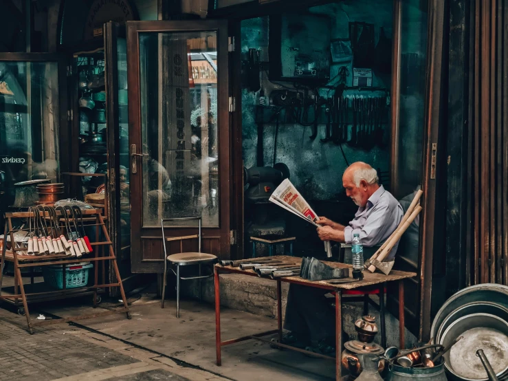 an older man is reading a newspaper outside a store