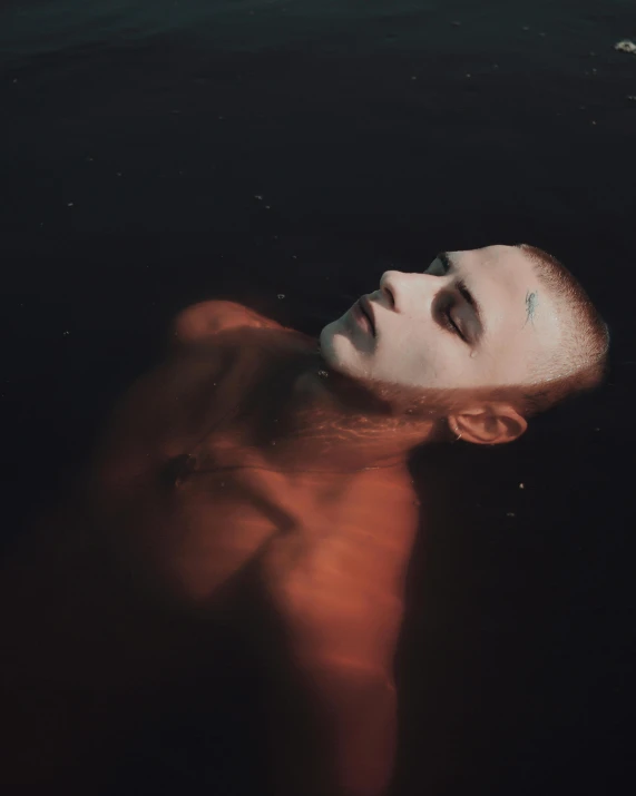 man with shaved head swimming in the water