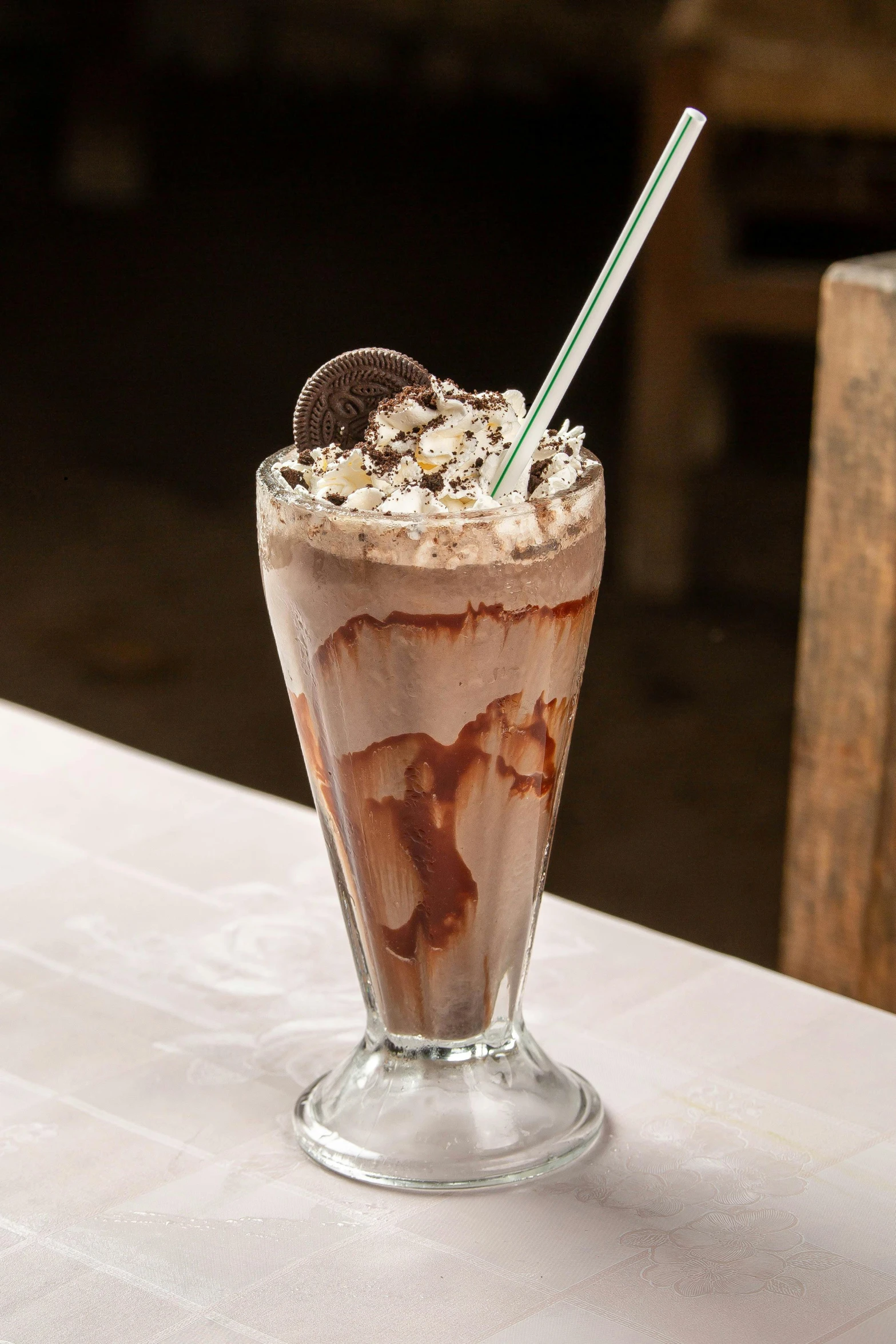 a cup on a table with chocolate and oreo ice cream