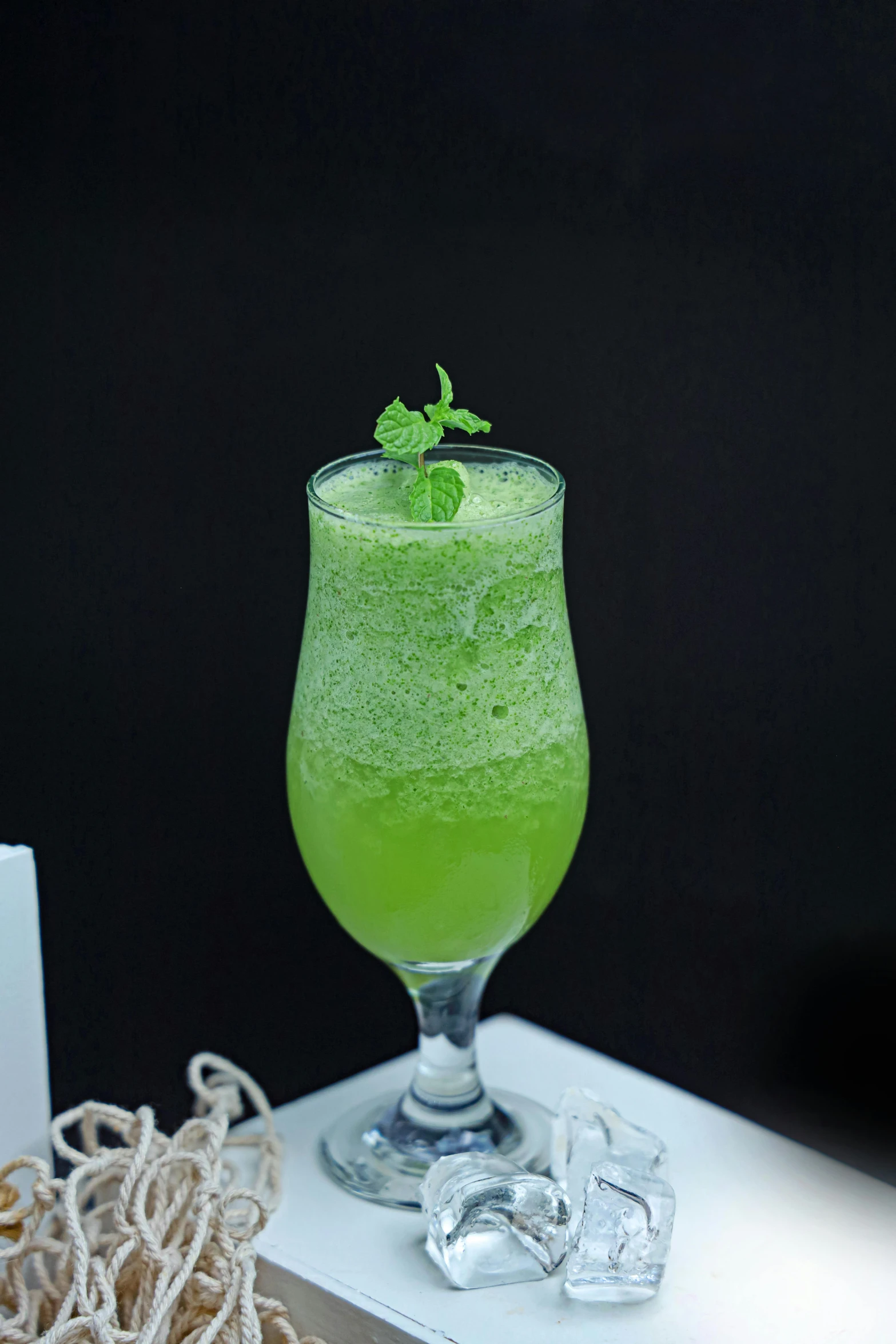 the green drink in a glass with a mint sprig on it