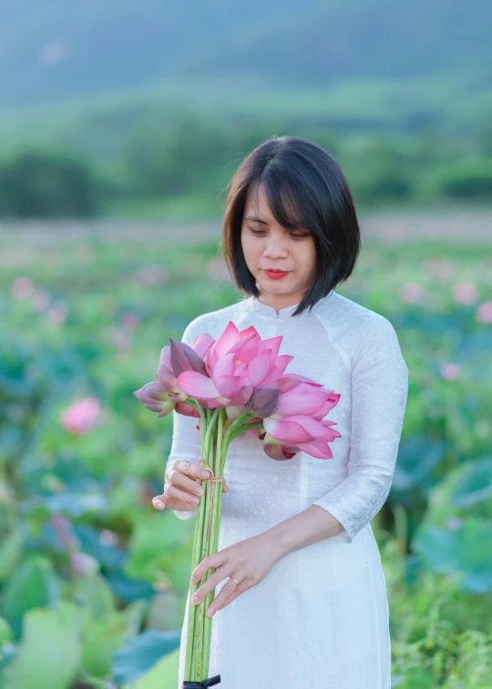 a woman in a white dress holding a pink flower