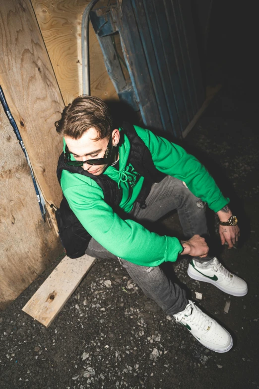 a man in a green jacket sits on the ground