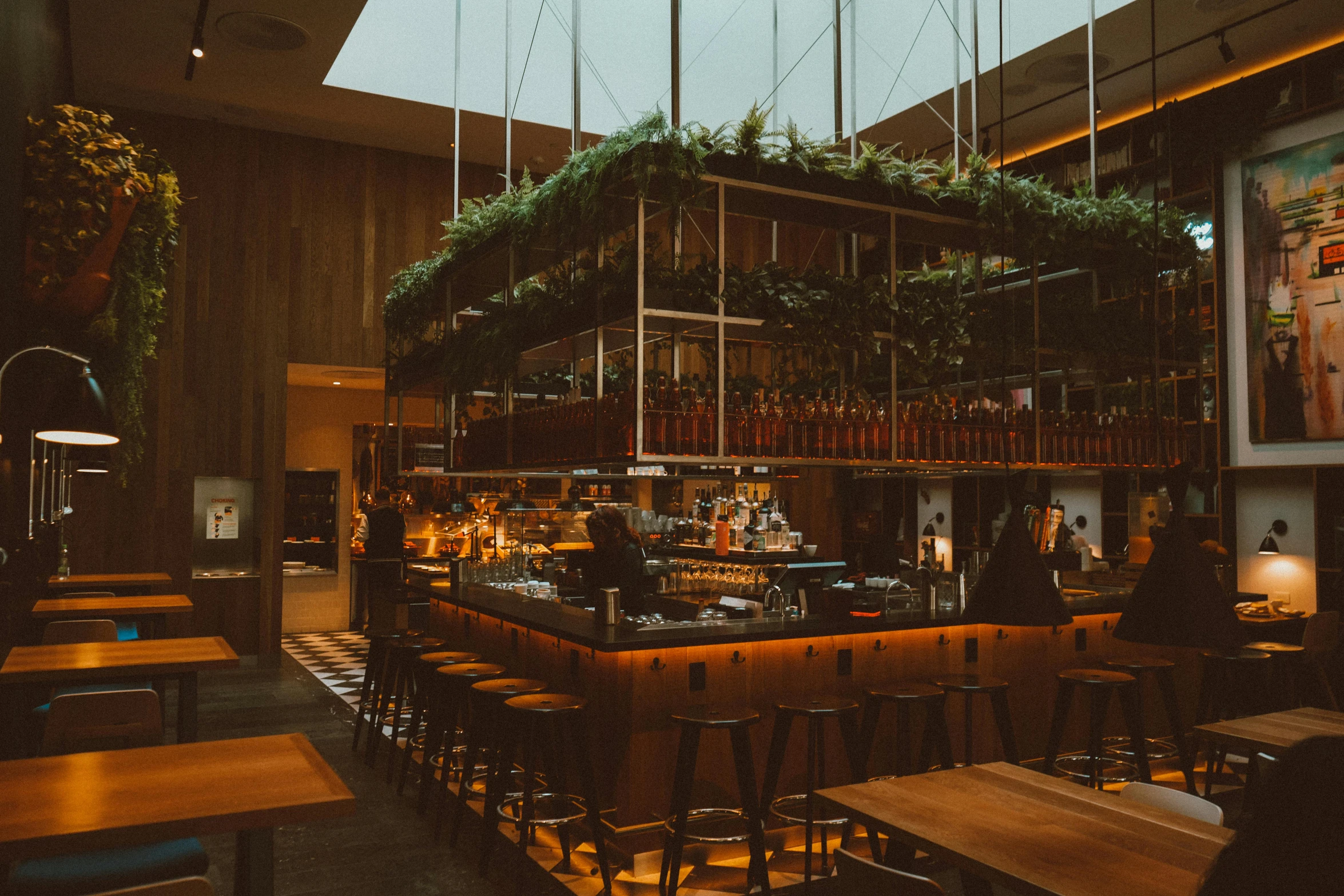 a dining area with tall wooden tables and plants growing on top