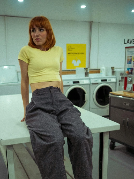 a woman sitting on a desk near a washer