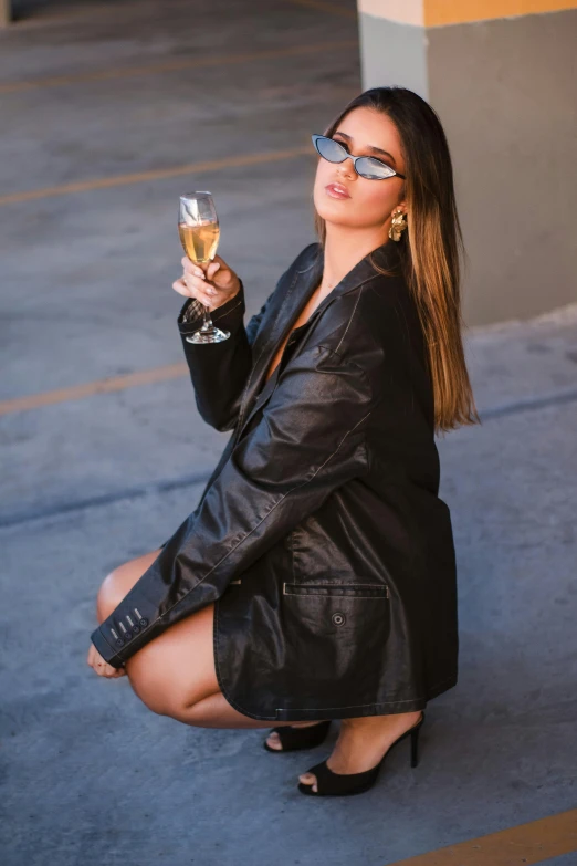 woman sitting on sidewalk drinking wine from glass