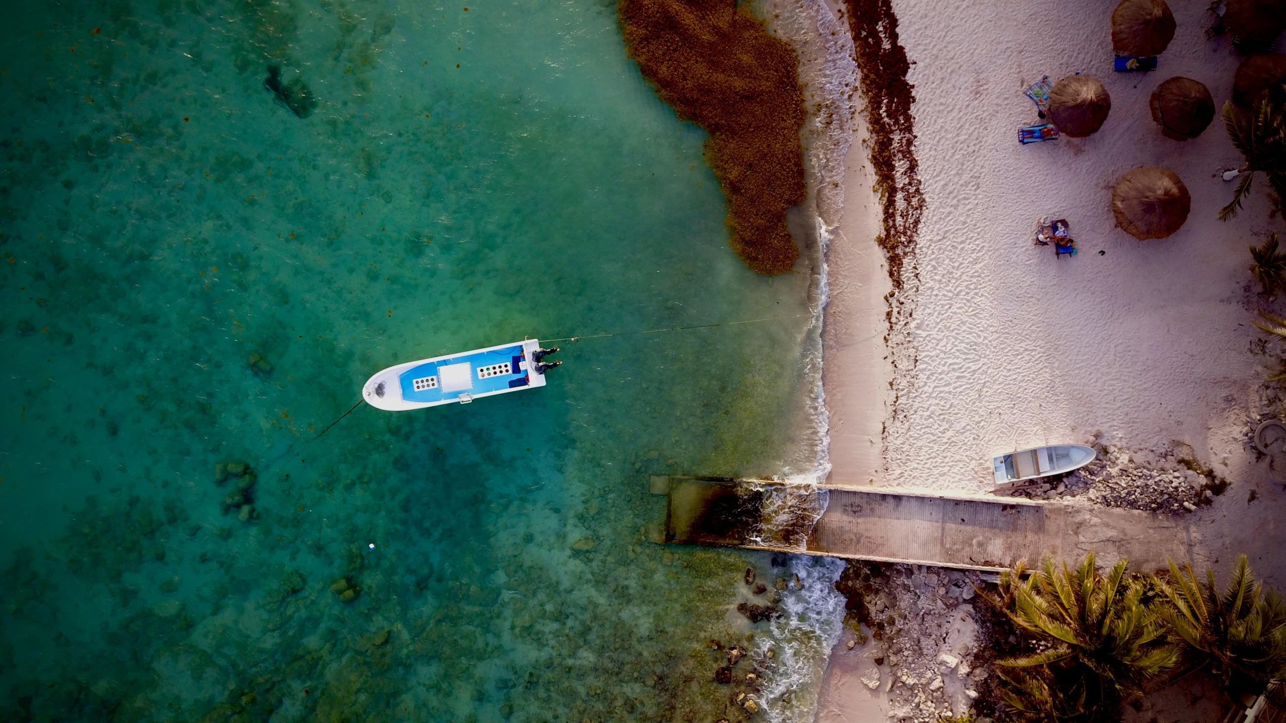 a boat moored at a pier that is on the beach