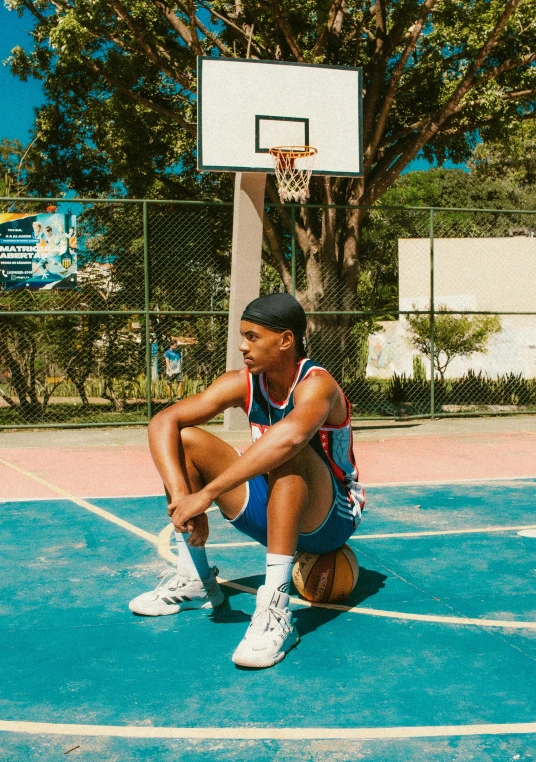 a basketball player on the court sits in a broken basketball hoop