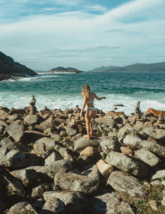 there is a woman that is running down rocks near the ocean