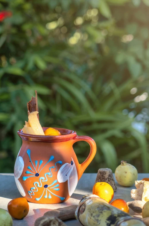 an orange mug sitting on a table with other fruits around it