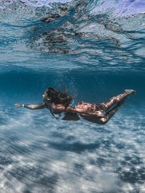 the woman is swimming under the water with her  out