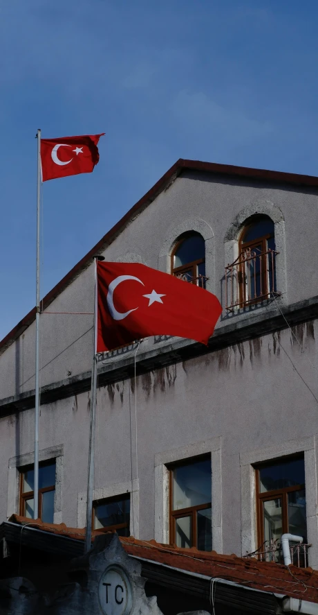 a flag flying outside a building with two flags near the ground
