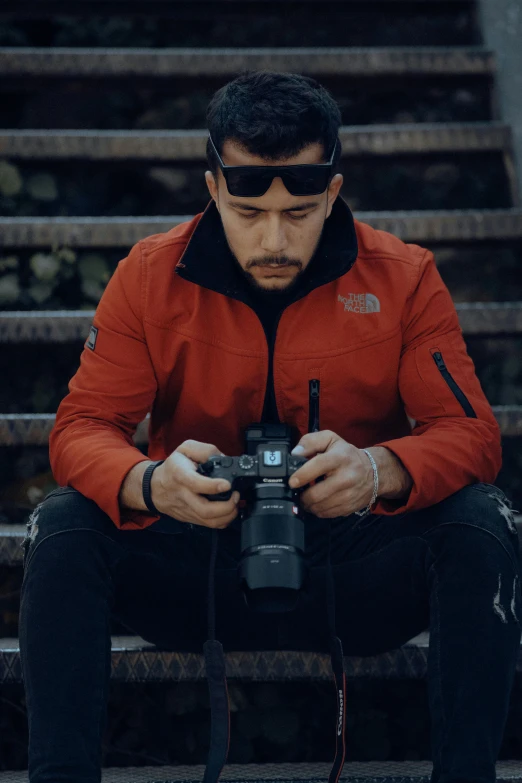 the pographer is seated down and looking at his camera