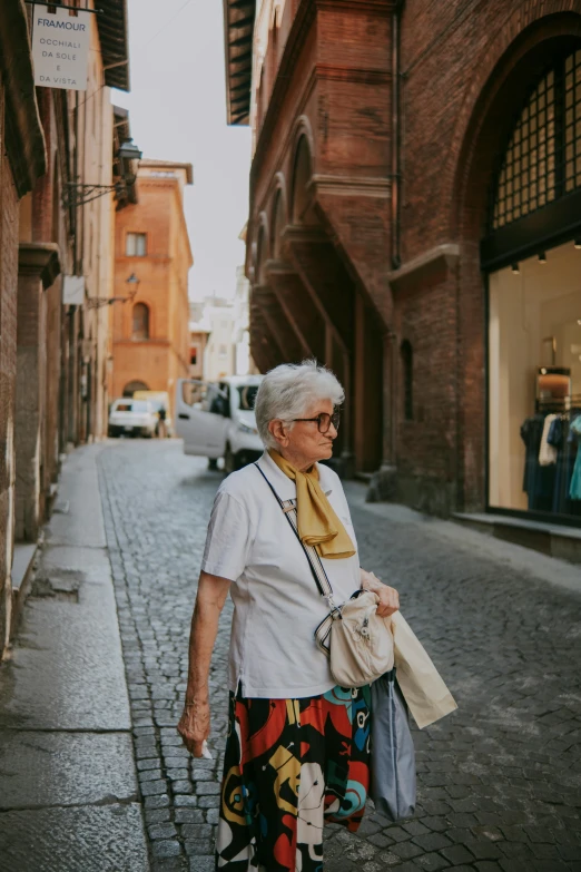 an elderly woman walking down the street carrying a purse