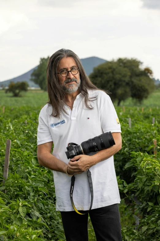 a man in the middle of a field holding a camera