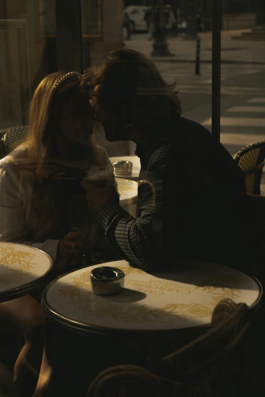 a man and woman at a table while looking at their cellphones