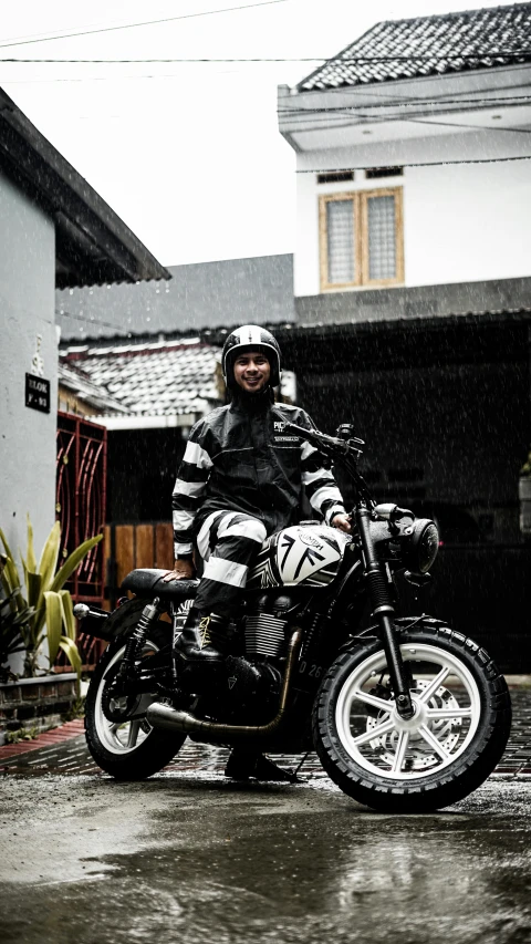 a man riding on the back of a motorcycle on a wet street