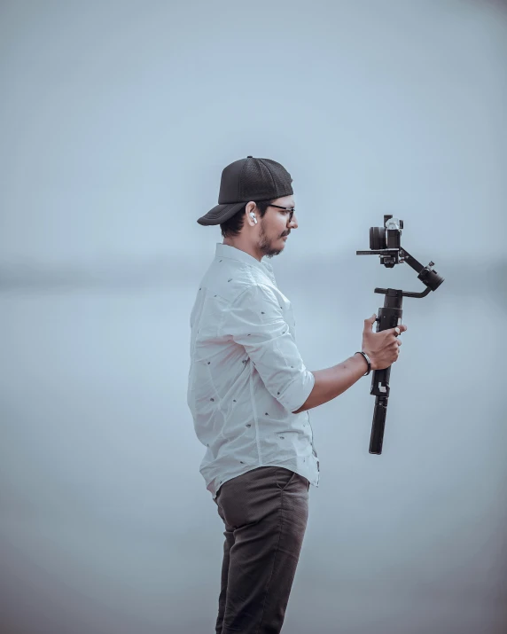 a man in white shirt holding a gun and standing on beach