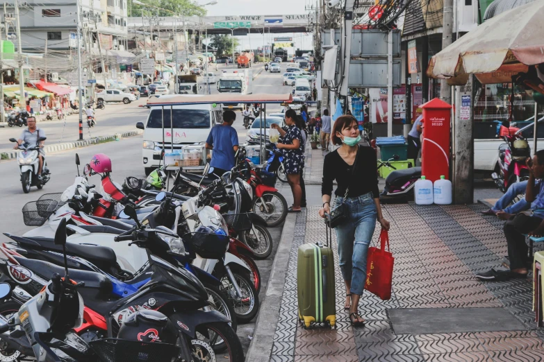 a woman holding a suitcase walks past parked motorcycles