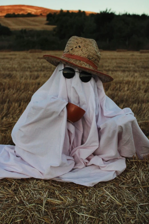 a person wearing a hat and sunglasses hides from the sun