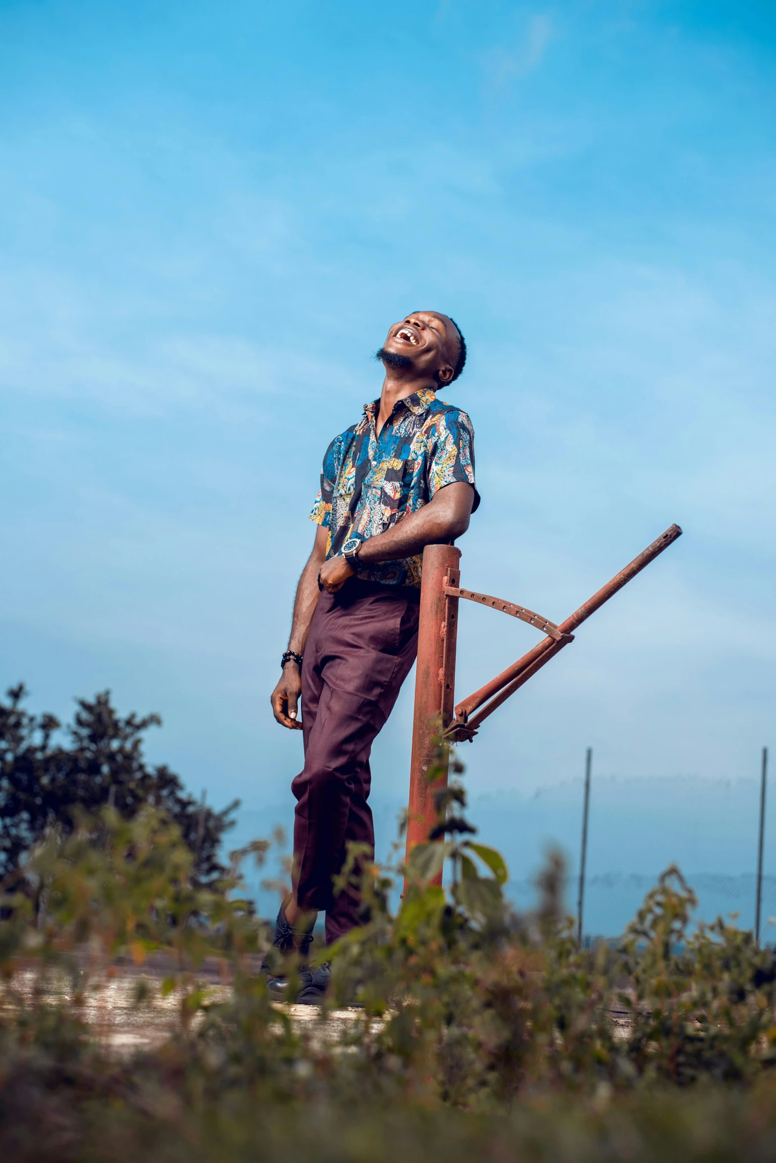 an african man with his eyes closed and leaning against a wooden post