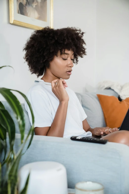 a young woman on a couch watching soing on her laptop