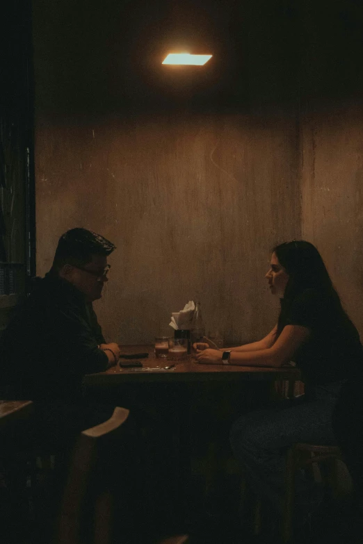 two people sitting at a table in a dark room