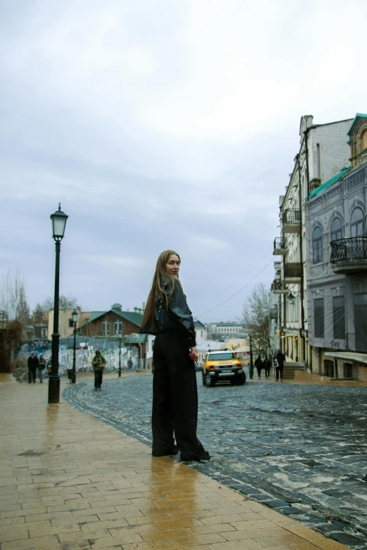 a young woman stands on a street corner in the rain