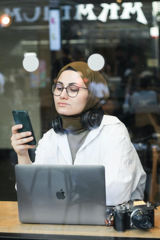 a woman in glasses on the phone and a laptop