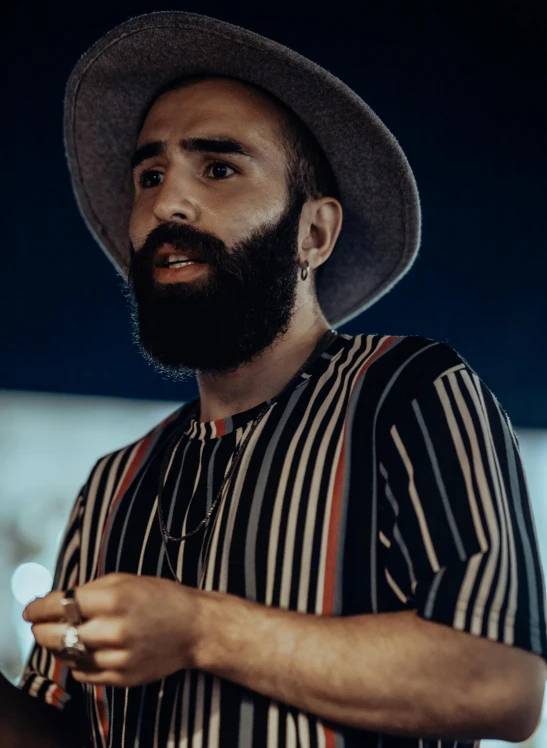 a bearded man with a hat and wearing a striped shirt