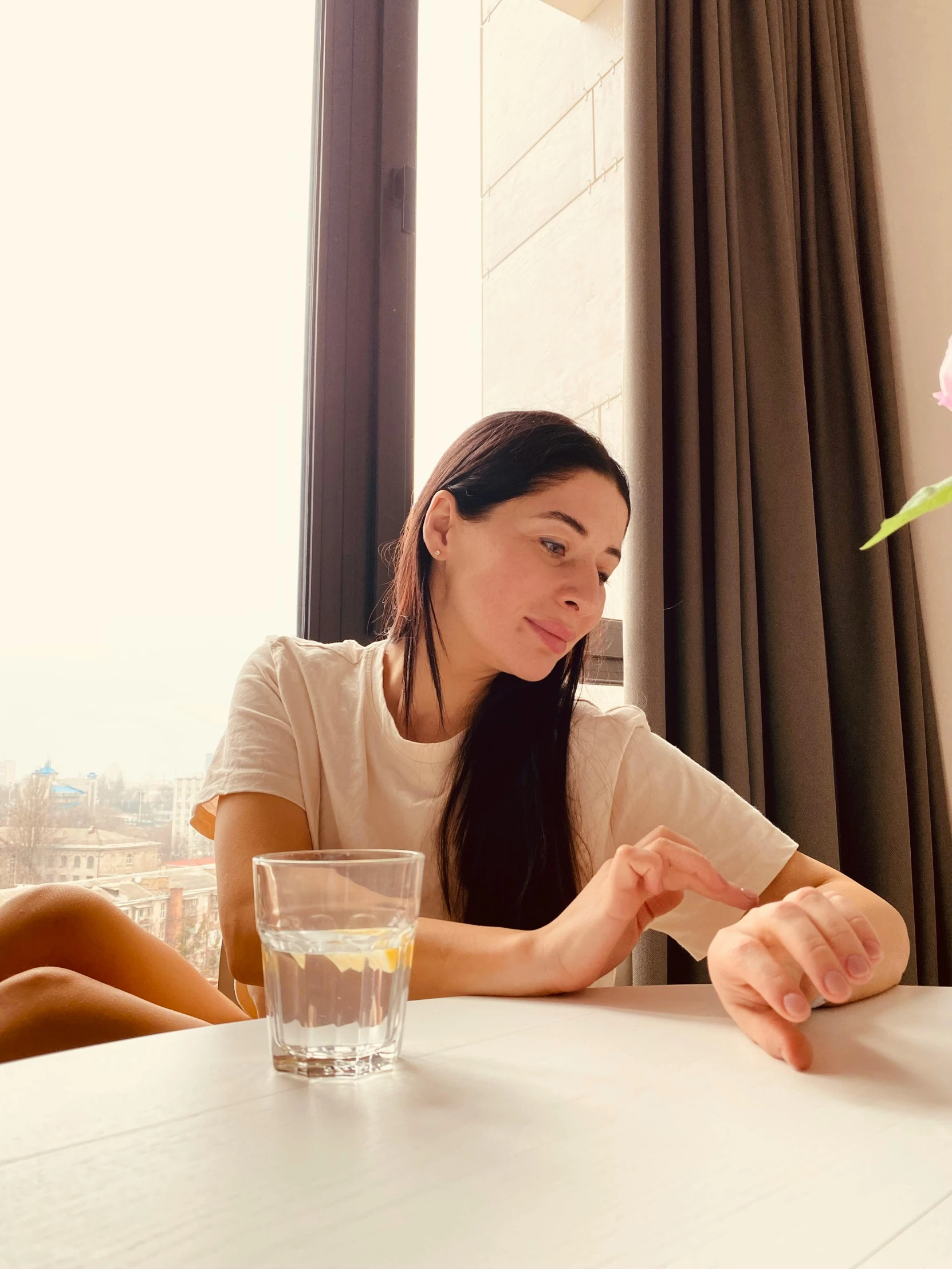 the woman sits at a table with a vase of flowers