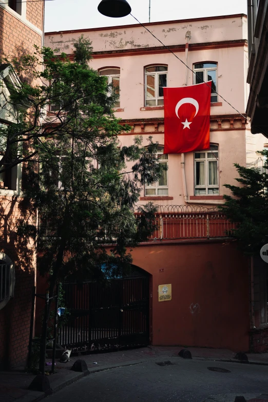 a large red flag with a turkish symbol hanging from the side of a building
