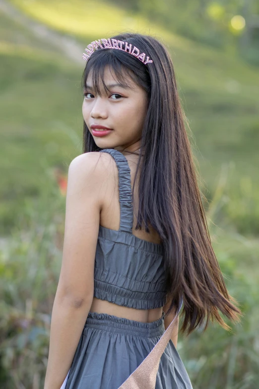 a girl in a gray dress wearing a pink flower headband