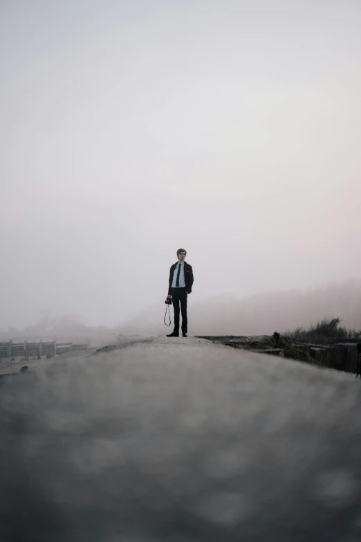 there is a man standing on a street near the fog