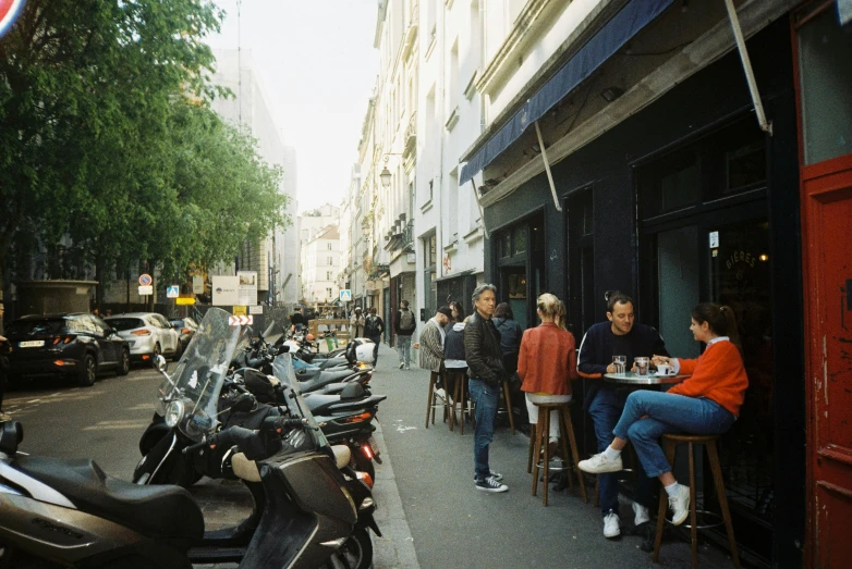 a city street with people sitting at tables and parked motorcycles