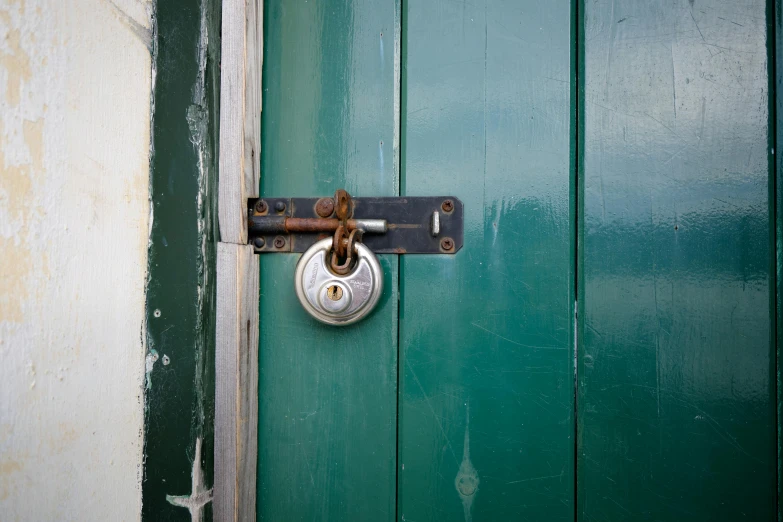 the door is green with white paint and a large padlock