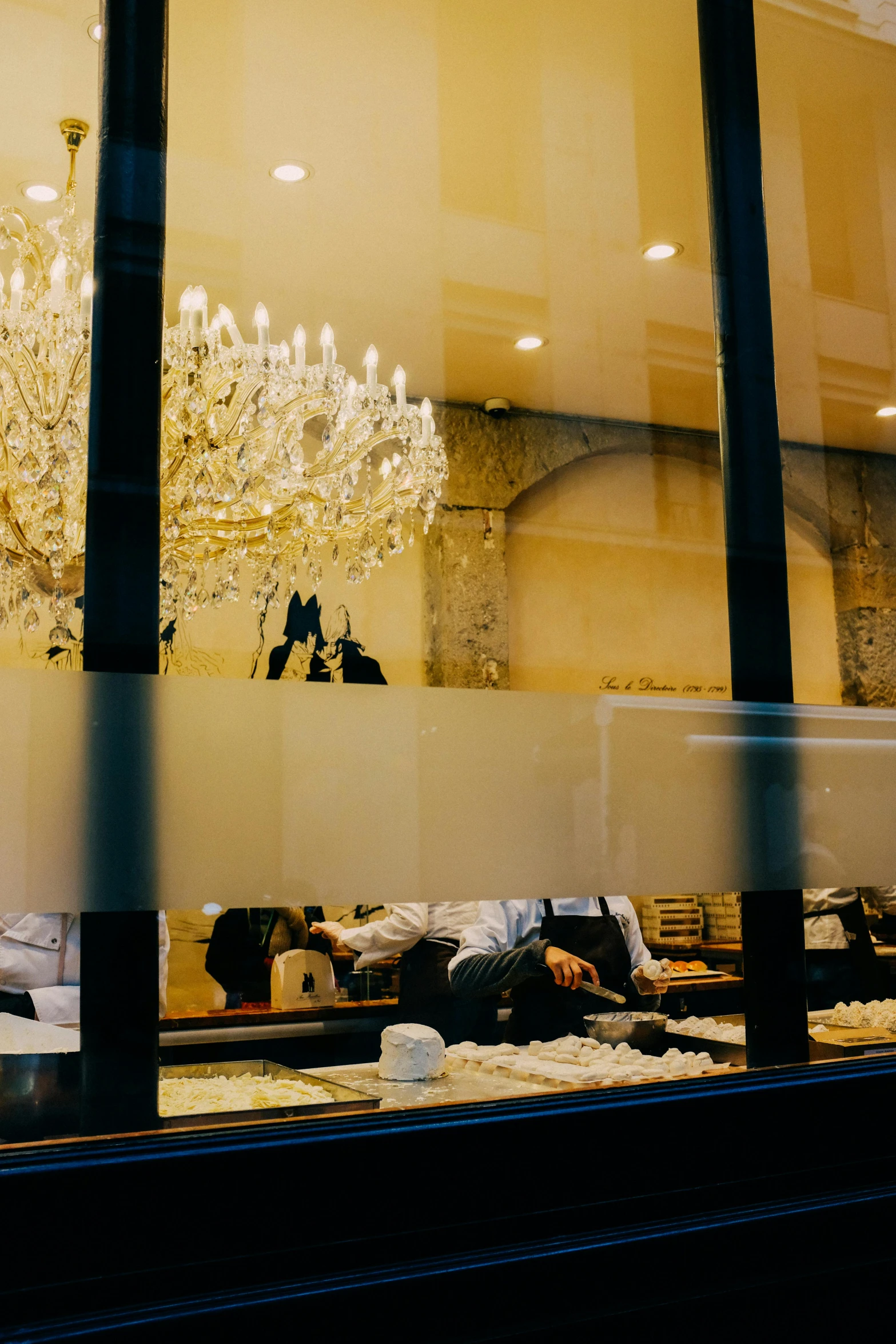 the glass is reflecting a chandelier and it is reflecting a man sleeping on the floor