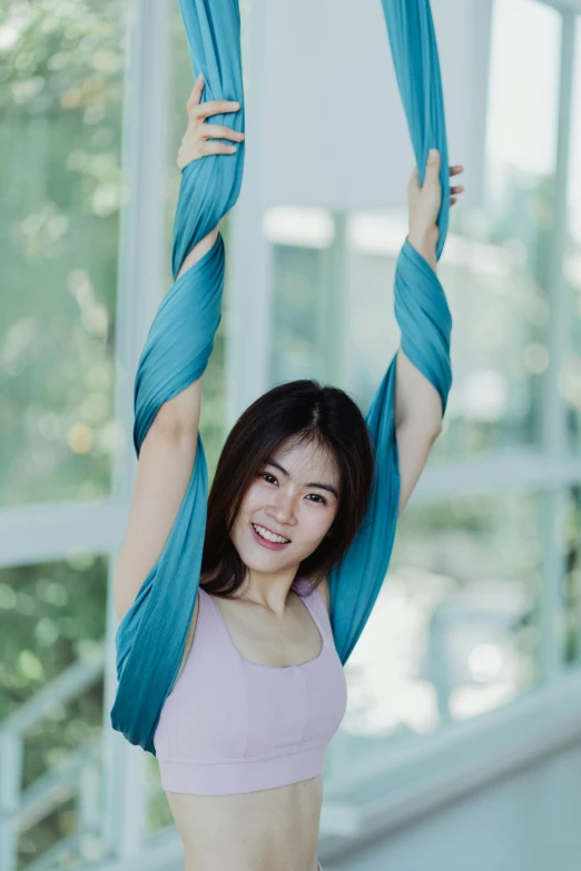 a woman is smiling and holding a scarf in the air