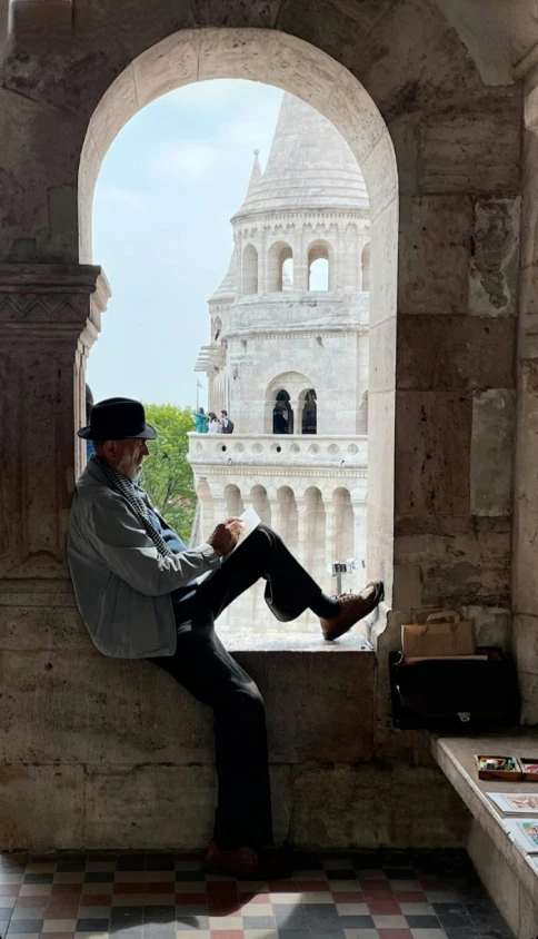 a man sitting on top of an old building next to a window