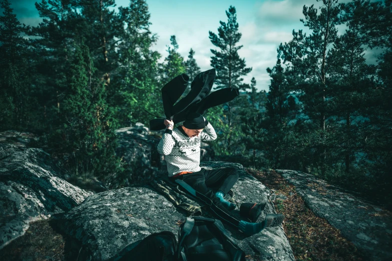 a person wearing a cowboy hat is sitting on a rock