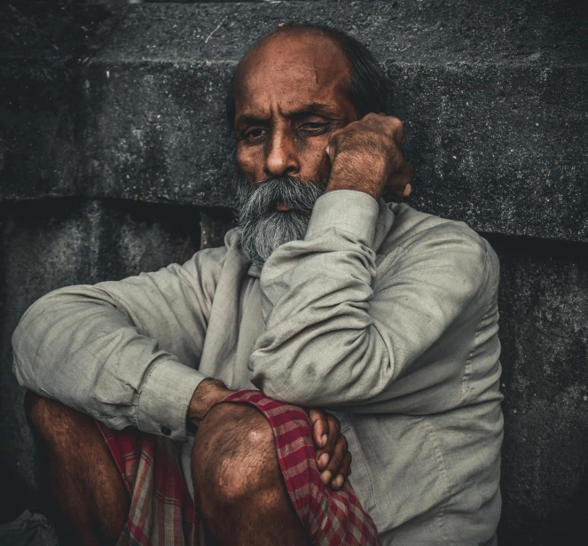 an older man in grey shirt sitting and posing