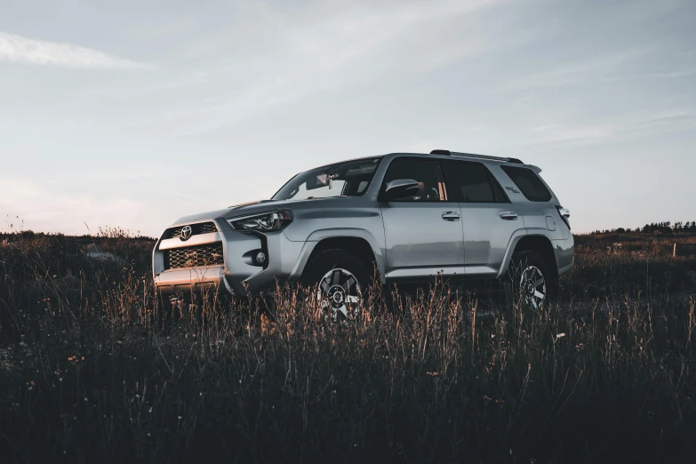 a silver suv is in a field with grass