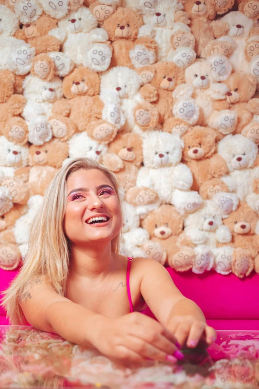 a woman sitting with teddy bears on the wall in the background