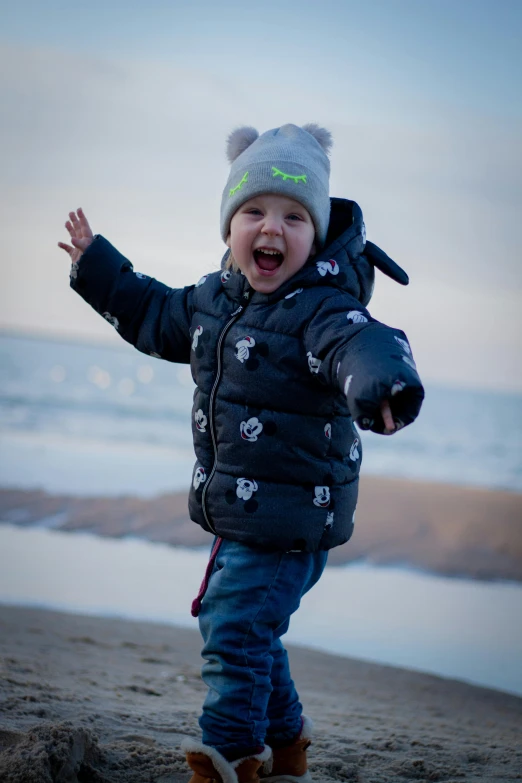 a  wearing a coat, standing on the beach