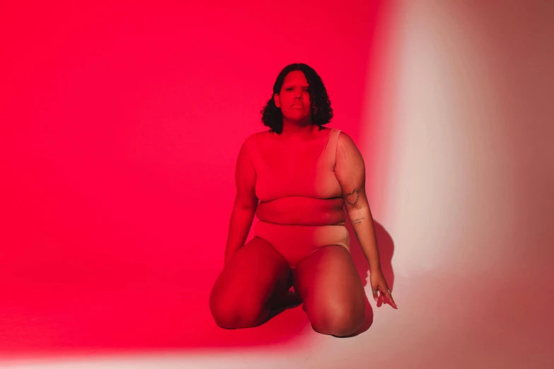 a woman in a red bathingsuit crouching in the dark