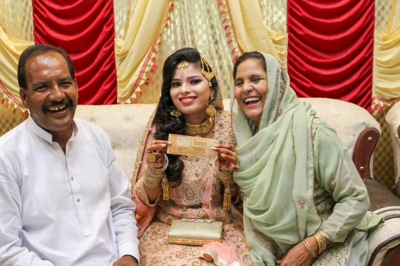 three people are sitting on a couch and posing for a picture