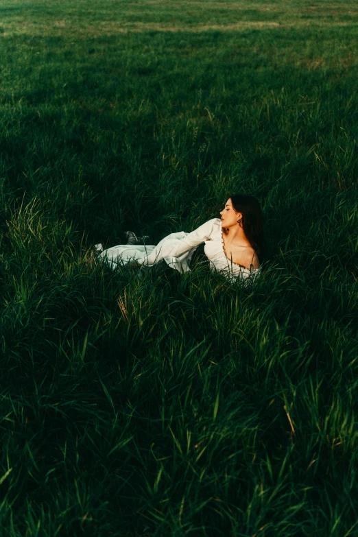 a beautiful woman laying in a grassy field